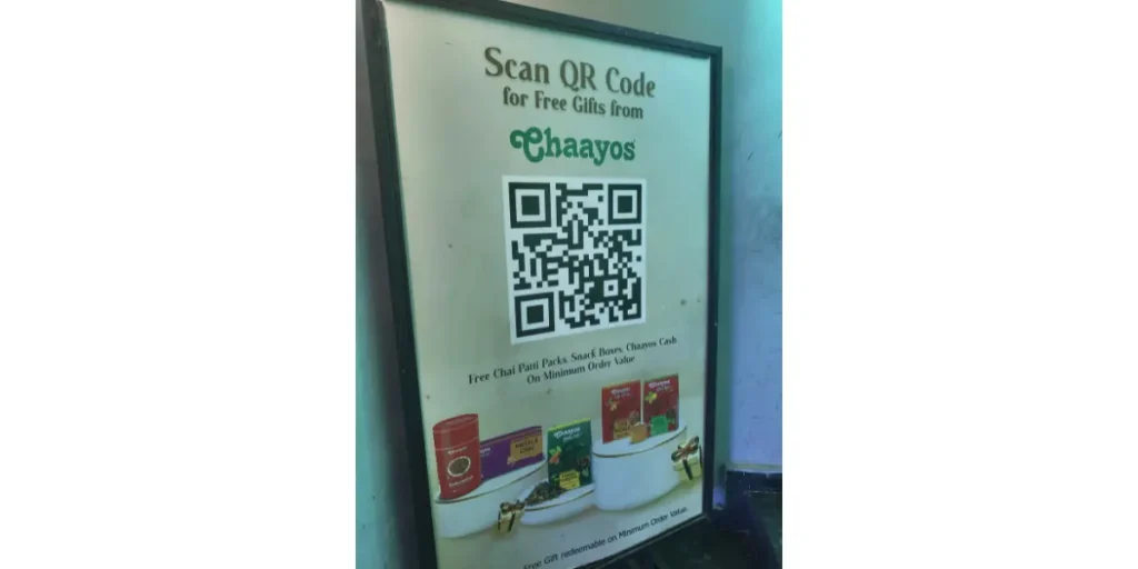 A standing printed board with a Chaayos advertisement and a QR code to register and claim free gifts.