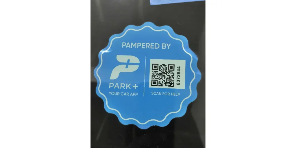 A blue Park+ app sticker with a QR code on a car, with the CTA "Scan for Help" to access the app.