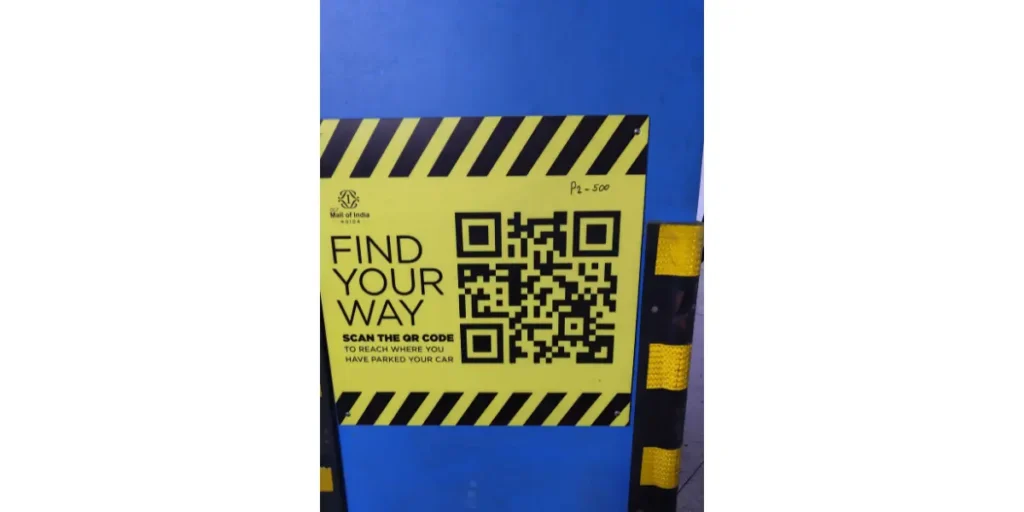 Black QR code on a yellow poster in a parking lot for locating your car.