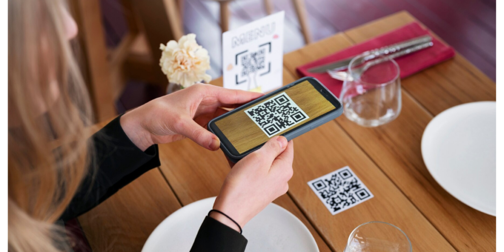 A hand scanning a cafe QR Code that's there on a table.