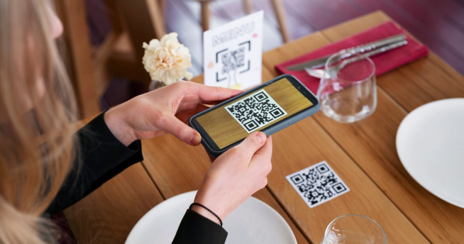 A hand scanning a cafe QR Code that's there on a table.