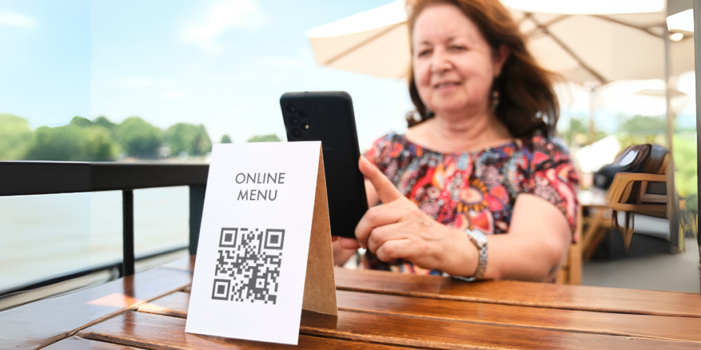 A woman scanning a QR Code from a table tent with "Online Menu" written on it. 