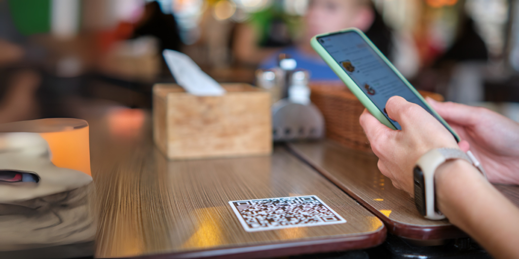 A table with a restaurant QR Code on it with a tissue box in the background.