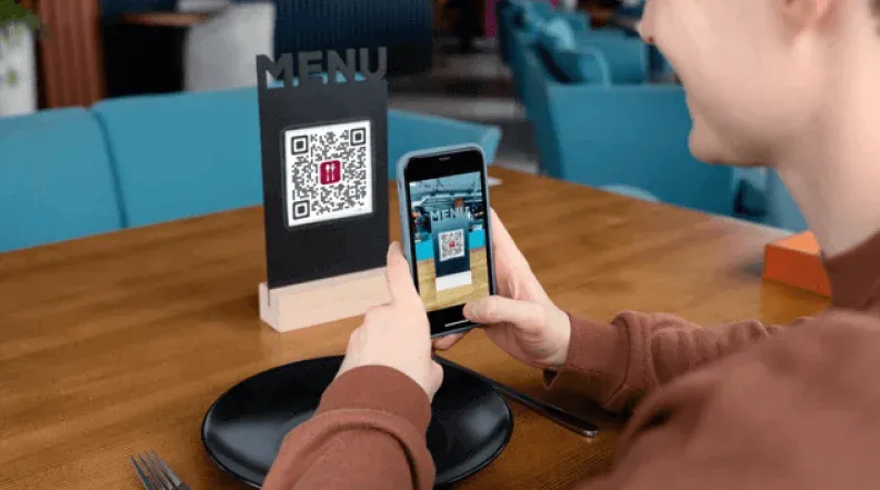 Imagen que muestra a un cliente escaneando un código QR en un restaurante